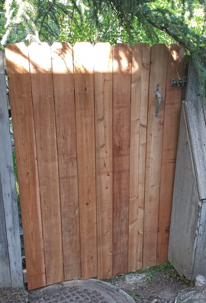 A cedar fence door has new pickets installed.