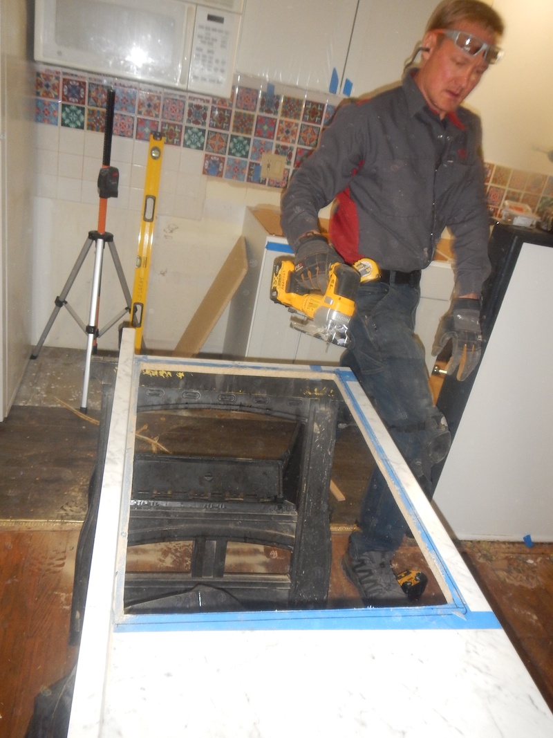 A handyman finishes cutting a hole in a countertop for a new sink.