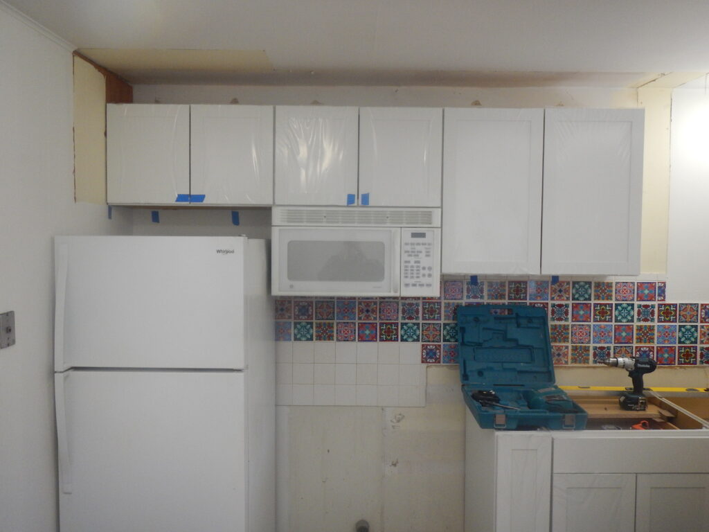 New upper kitchen cabinets are prepped for knobs during a small condo remodel in Aspen.