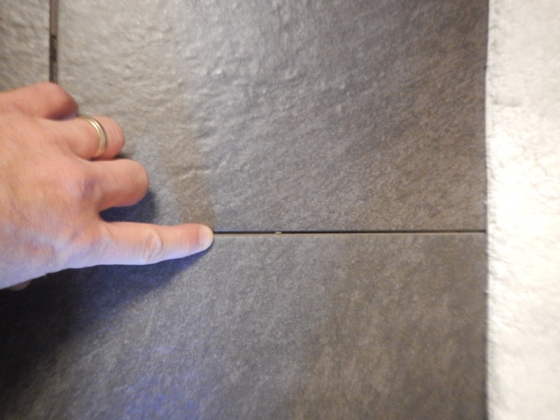 Missing grout in a bathroom tile floor.